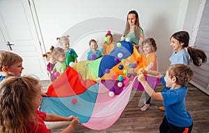 Schoolchildren playing using parachute with friends in gym