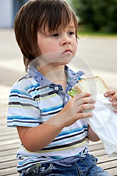 Schoolchildren, preschooler, boy eating his lunch, snack, breakfast in the school yard. Food for children in educational