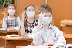 Schoolchildren with protection masks against flu virus at lesson in class