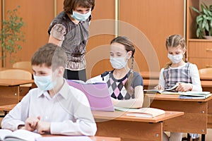 Schoolchildren with protection masks against flu virus at lesson in classroom