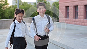 Schoolchildren pupils little boy schoolboy with book and hispanic schoolgirl child girl brother and sister friends wear