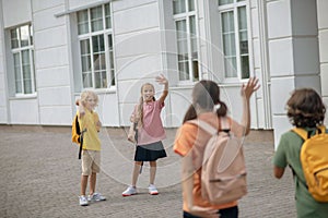 Schoolchildren in the school yard greeting each other keeping distance photo