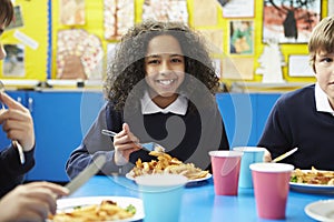 Schoolchildren Sitting At Table Eating Cooked Lunch photo