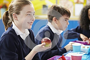 Schoolchildren Sitting At Table Eating Packed Lunch