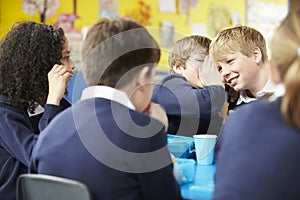 Schoolchildren Sitting At Table Eating Packed Lunch