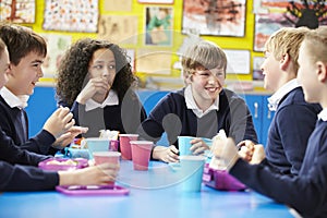 Schoolchildren Sitting At Table Eating Packed Lunch