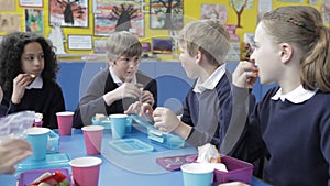 Schoolchildren Sitting At Table Eating Packed Lunch