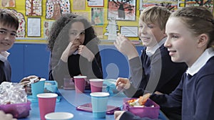 Schoolchildren Sitting At Table Eating Packed Lunch