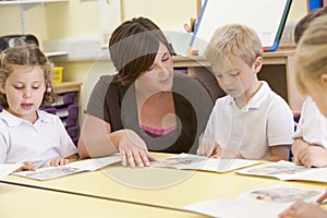 Schoolchildren and their teacher reading in class