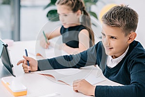 Schoolchildren writing in blank exercise books while studying at desk