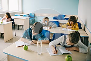 schoolchildren writing in notebooks on lesson