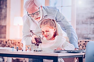 Schooler blinking while using microscope sitting at desk