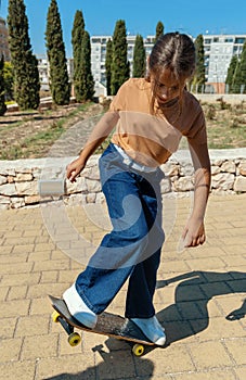 Schooler girl learning to ride a skateboard in park