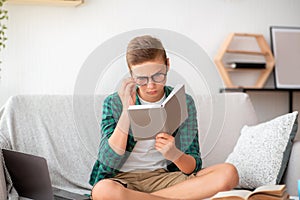 Schooler in glasses reading book at home