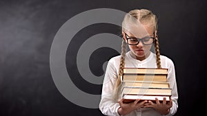 Schoolgirl angrily looking heap of books, hating lessons and education, problem