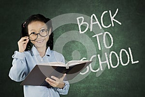 Schoolgirl with back to school word on chalkboard