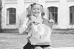 Schoolgirl with backpack relax outdoors, waiting school bus concept