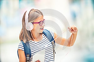 Schoolgirl with bag, backpack. Portrait of modern happy teen school girl with bag backpack headphones and tablet.