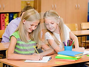 Schoolgirl cheating at exam, looking at a friend's writing