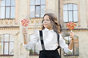 Schoolgirl choosing sweets. Happy kid with sweet candy. Kid child holding lollipops candy outdoors. Happy kid with candy