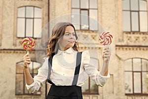 Schoolgirl choosing sweets. Happy kid with sweet candy. Kid child holding lollipops candy outdoors. Happy kid with candy