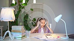 Schoolgirl completes homework and turns the music on phone. distance learning.