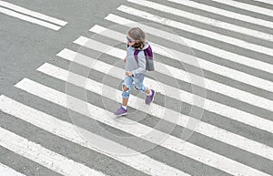 Schoolgirl crossing road on way to school. Zebra traffic walk way in the city. Concept pedestrians passing a crosswalk. Stylish