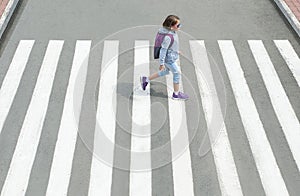 Schoolgirl crossing road on way to school. Zebra traffic walk way in the city. Concept pedestrians passing a crosswalk. Stylish