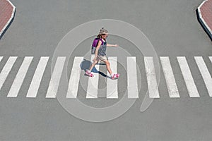 Schoolgirl crossing road on way to school. Zebra traffic walk way in the city. Concept pedestrians passing a crosswalk. Stylish