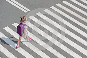 Schoolgirl crossing road on way to school. Zebra traffic walk way in the city. Concept pedestrians passing a crosswalk. Stylish