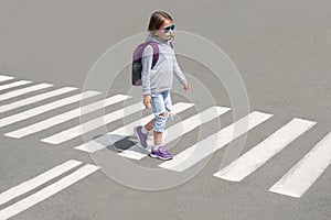 Schoolgirl crossing road on way to school. Zebra traffic walk way in the city. Concept pedestrians passing a crosswalk. Stylish