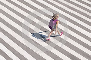 Schoolgirl crossing road on way to school. Zebra traffic walk way in the city. Concept pedestrians passing a crosswalk. Stylish