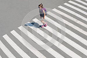 Schoolgirl crossing road on way to school. Zebra traffic walk way in the city. Concept pedestrians passing a crosswalk. Stylish