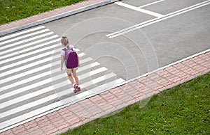 Schoolgirl crossing road on way to school. Zebra traffic walk way in the city. Concept pedestrians passing a crosswalk. Stylish