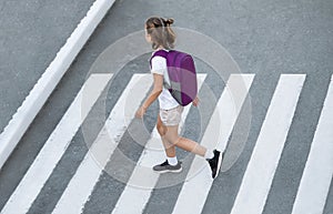 Schoolgirl crossing road on way to school. Zebra traffic walk way in the city. Concept pedestrians passing a crosswalk.  Stylish