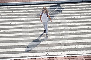 Schoolgirl crossing road on way to school. Zebra traffic walk way in the city. Concept pedestrians passing a crosswalk.  Stylish