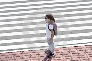 Schoolgirl crossing road on way to school. Zebra traffic walk way in the city. Concept pedestrians passing a crosswalk.  Stylish