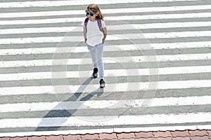 Schoolgirl crossing road on way to school. Zebra traffic walk way in the city. Concept pedestrians passing a crosswalk. Stylish