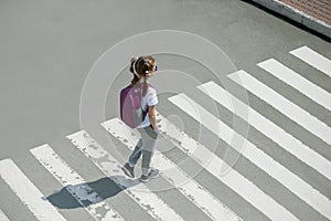 Schoolgirl crossing road on way to school. Zebra traffic walk way in the city. Concept pedestrians passing a crosswalk.  Stylish