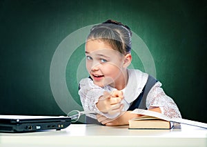 Schoolgirl does lessons sitting behind a desk