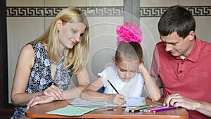 Schoolgirl doing homework with their parents smile looked into the frame