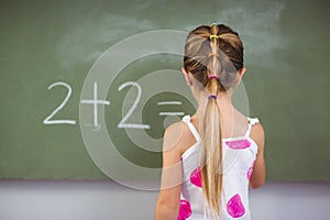 Schoolgirl doing mathematics on chalkboard in classroom