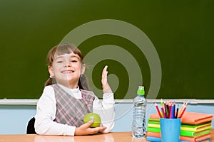 Schoolgirl elementary school raising hands knowing the answer to question