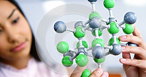 Schoolgirl experimenting molecule model in laboratory at school