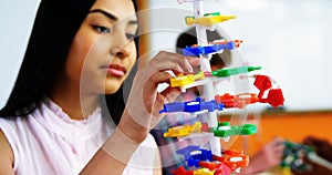 Schoolgirl experimenting molecule model in laboratory at school