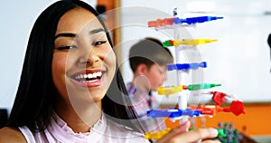 Schoolgirl experimenting molecule model in laboratory at school