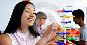 Schoolgirl experimenting molecule model in laboratory at school