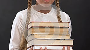 Schoolgirl in eyeglasses holding books against blackboard, education, geek