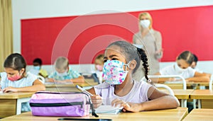 Schoolgirl in face mask working at lesson