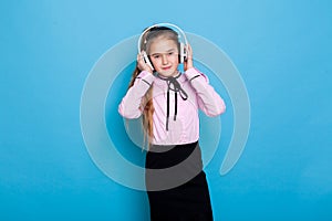 Schoolgirl girl listens to music in big headphones